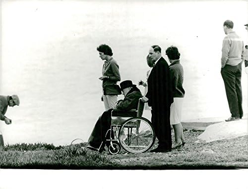 Реколта снимка на мъжете, толкающего инвалидна количка на Уинстън Чърчил по травяному поле.